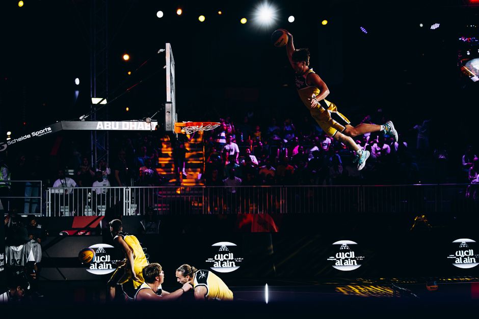 Basketball player performing an impressive slam dunk during an Abu Dhabi sports event.