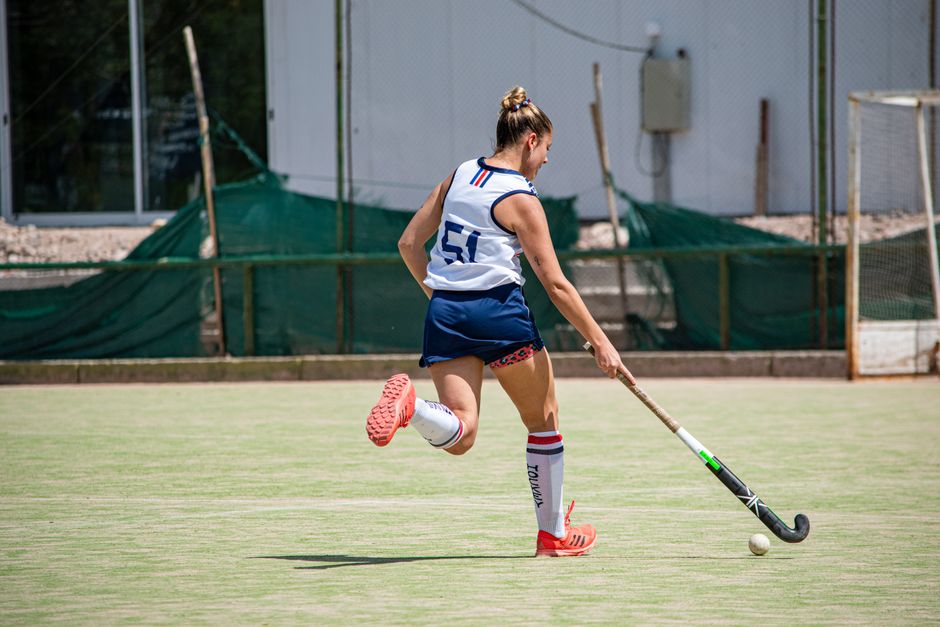 Female athlete playing field hockey outdoors on a sunny day.
